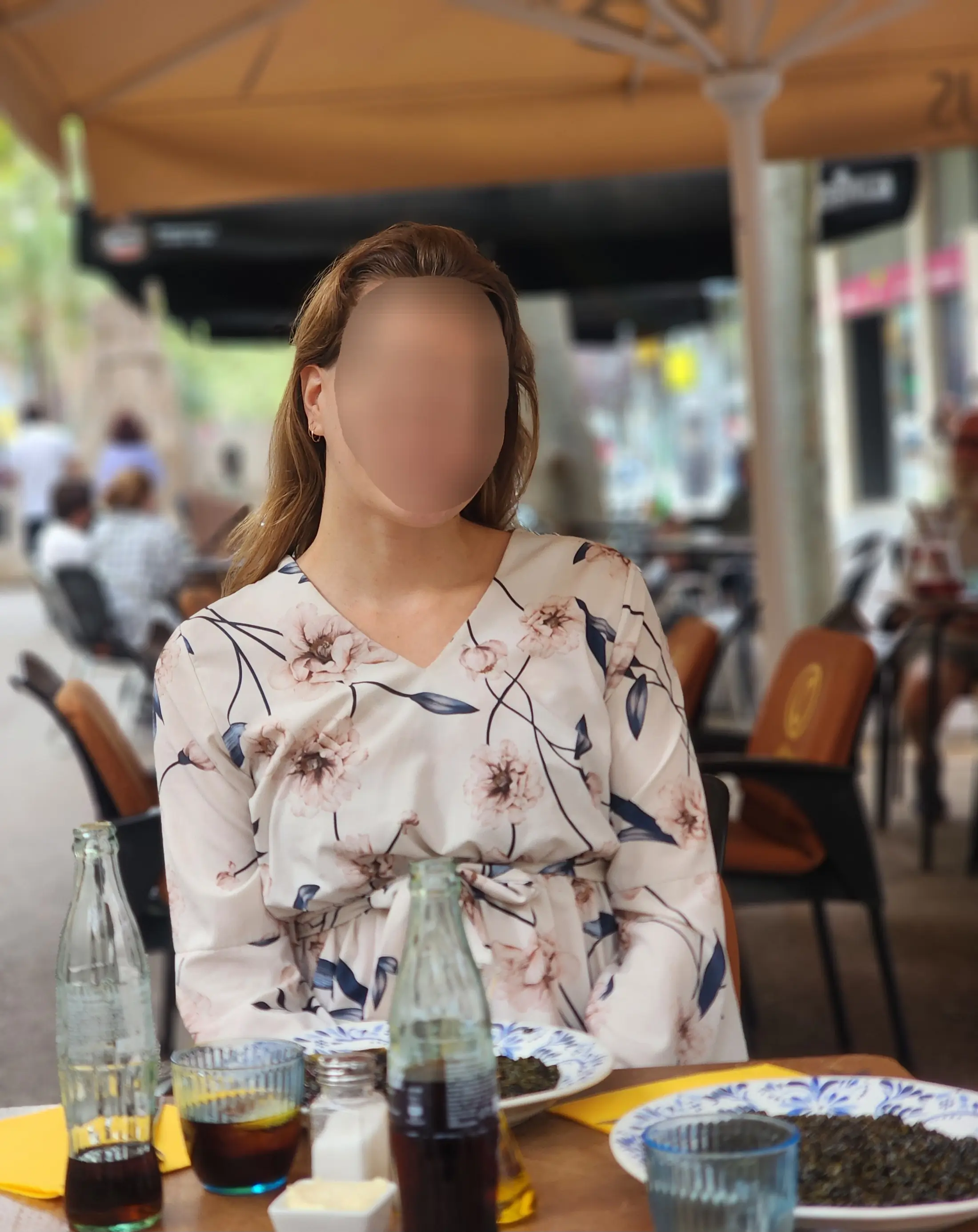 Josefine in a floral dress dining outdoors at a charming city café.