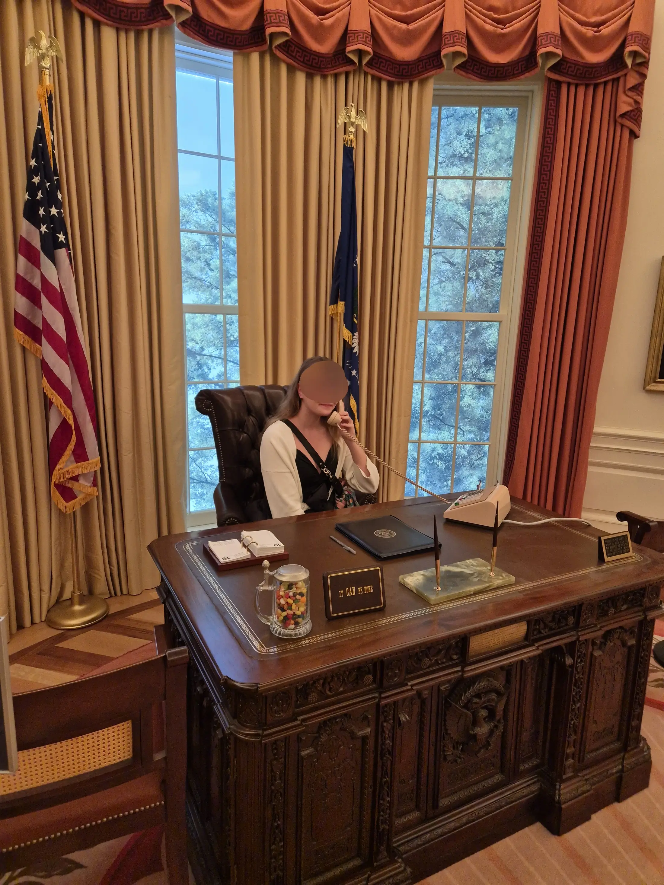 Josefine sits at an ornate desk, speaking on the phone in a grand, elegant office.