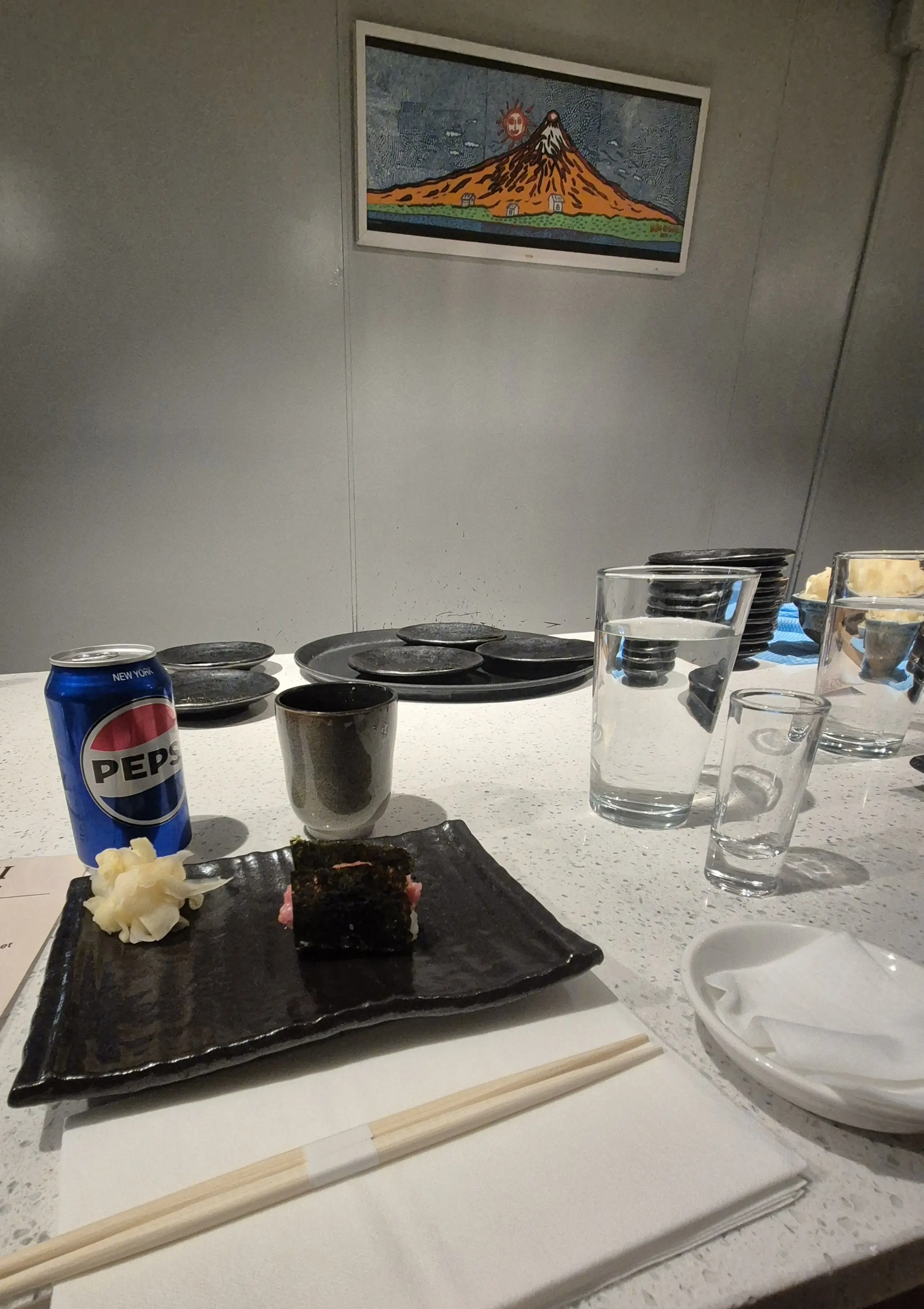 A minimalist sushi bar setting with a single maki roll and a can of Pepsi.